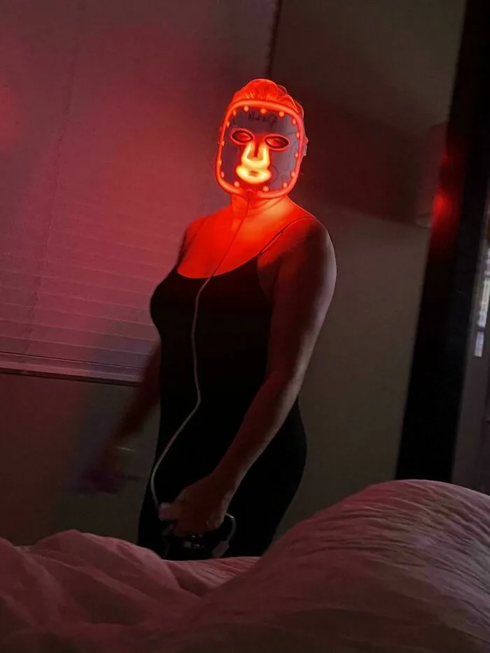 Mujer usando una máscara de terapia LED roja en la oscuridad, entre los errores tontos de novias y esposas.