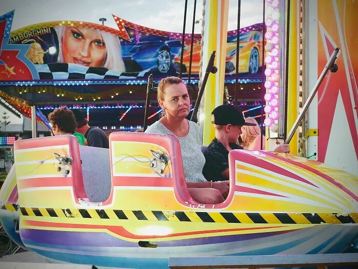 Mujer con expresión de aburrimiento en un juego mecánico, ilustrando errores tontos de novias y esposas.