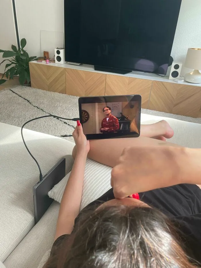 Novias y esposas viendo series en la tablet sostenida de forma inusual en el sofá