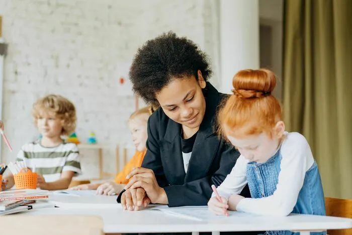 Profesora ayudando a una alumna en el aula, un sector clave entre las industrias que podrían colapsar.