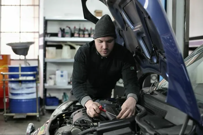 Mecánico trabajando en el motor de un coche, representando industrias tradicionales de automoción que van a colapsar