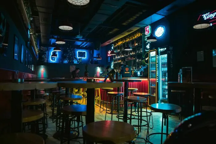 Interior de un bar nocturno vacío con luces de neón, ilustrando industrias de entretenimiento a punto de colapsar