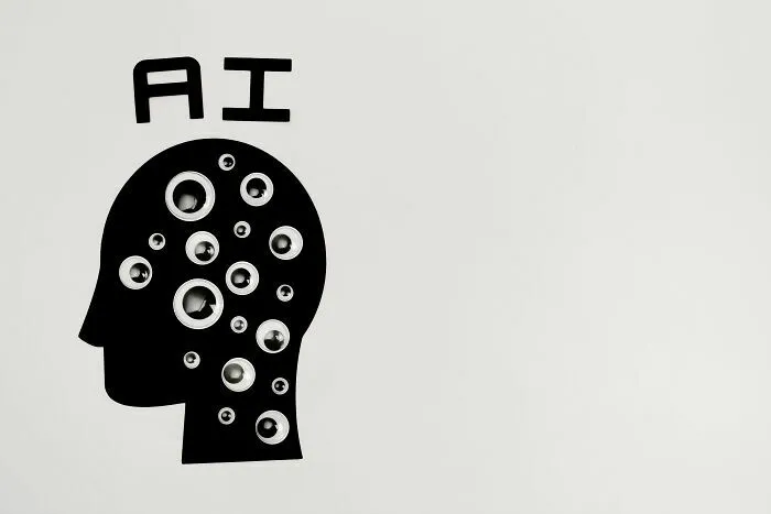Ilustración de cabeza con ojos y siglas de IA, simbolizando tecnologías que desplazan a industrias por colapsar