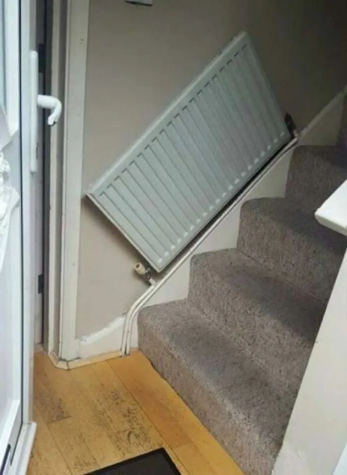 Instalación de radiador torcido en la escalera, un ejemplo de proyectos caseros fallidos.