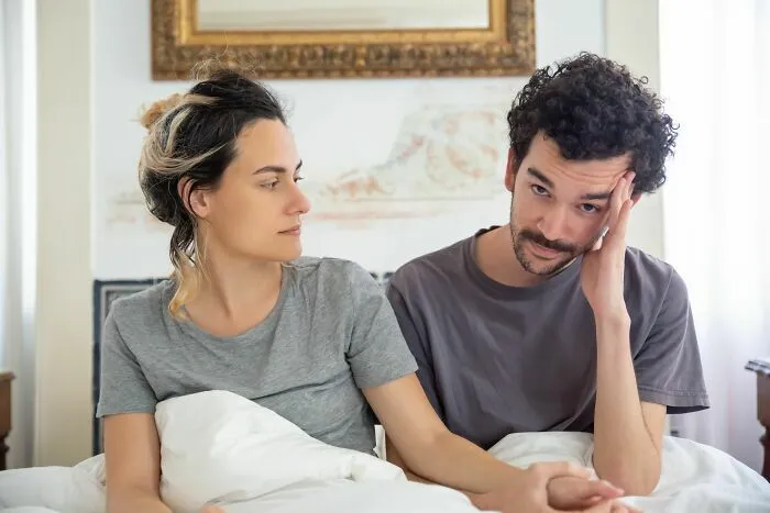 Pareja en la cama conversando sobre divertidas historias de gemelos confundidos