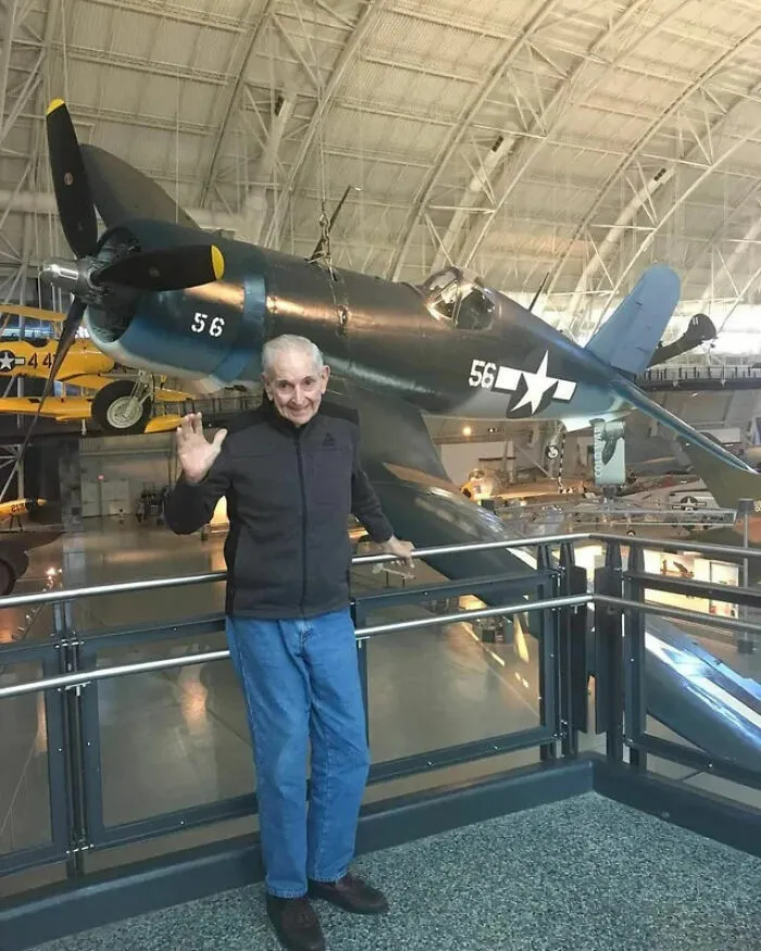 Hombre mayor junto a avión antiguo en museo de aviación histórica