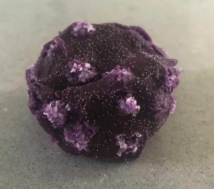 Mineral púrpura con cristales salinos en superficie rugosa
