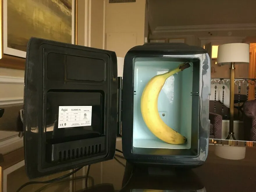 Mini refrigerador con una banana adentro en habitación de hotel