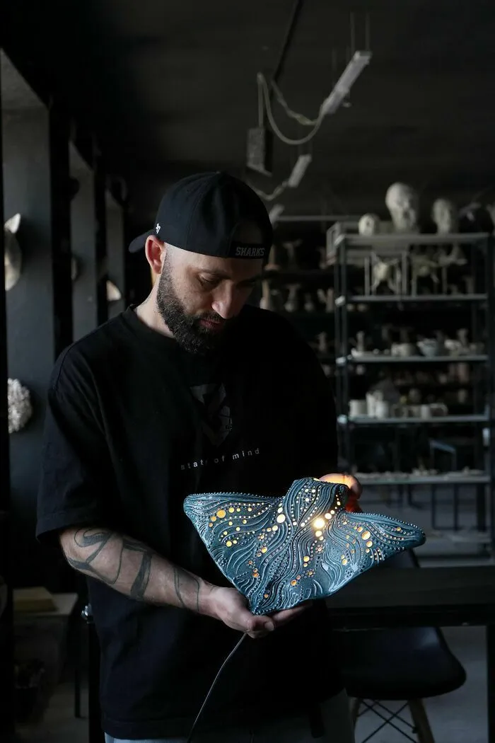 Artista mostrando una lámpara artesanal con diseño detallado en un taller de creaciones geniales