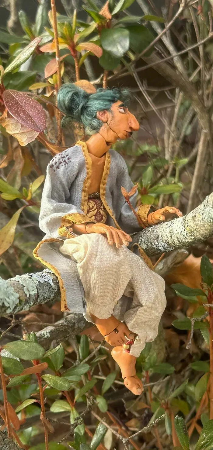Figura de arte artesanal sentada en rama de árbol en creación genial