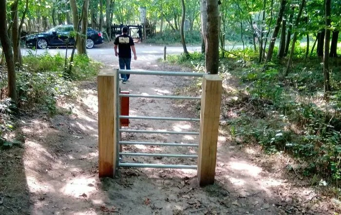 Barrera con diseño fallido que bloquea paso en camino de bosque.