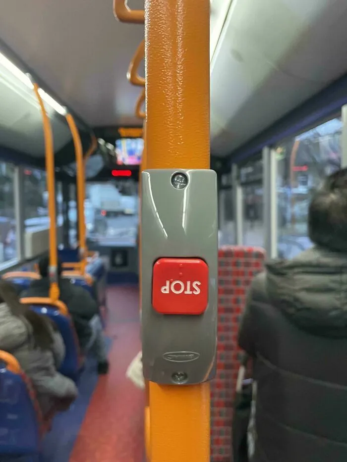Botón de parada invertido en barra de sujeción dentro de un autobús