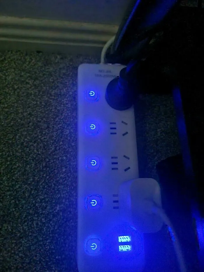 Regleta eléctrica con luces azules y botones de encendido visibles en oscuridad