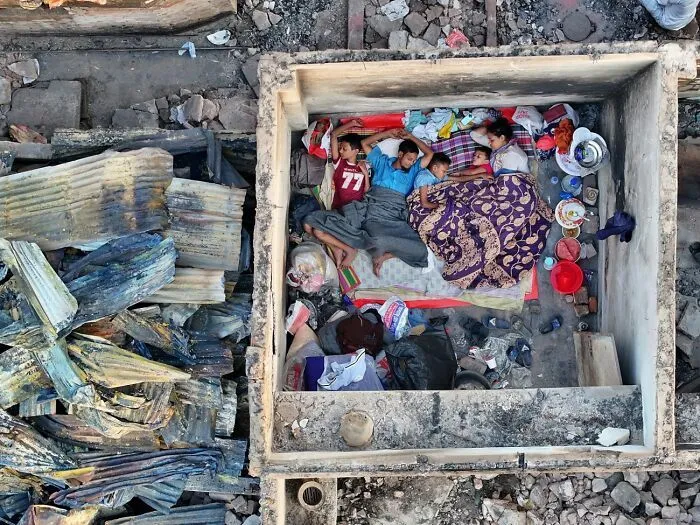 Familia durmiendo en habitación reducida entre escombros fotografía Siena 2026