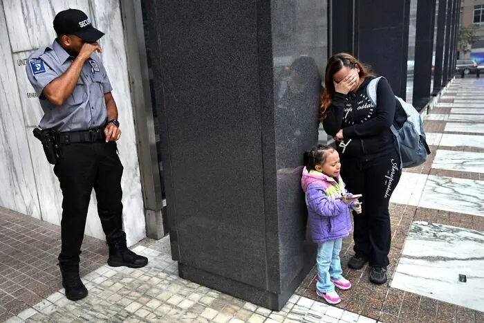 Mujer y niña llorando con guardia de seguridad en ciudad fotografía Siena 2026