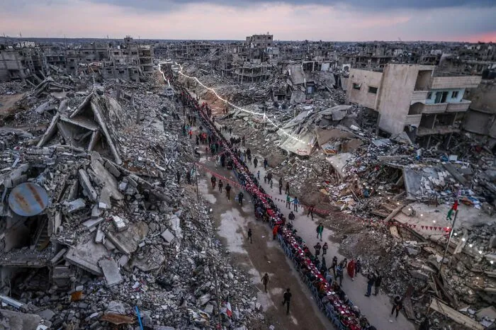 Imagen ganadora de zona destruida por conflicto con fila de personas en ruinas