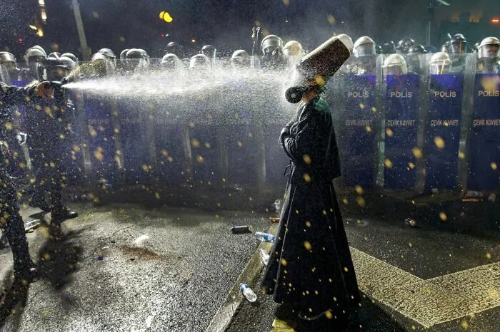 Foto premiada muestra policía rociando agua a manifestante con casco en protesta