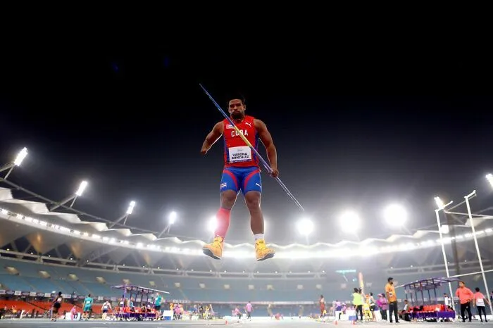 Atleta cubano compitiendo en jabalina en estadio iluminado por los Premios de fotografía Siena