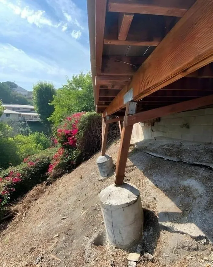 Cimientos de madera mal alineados sobre pilares de hormigón con fallos de construcción.