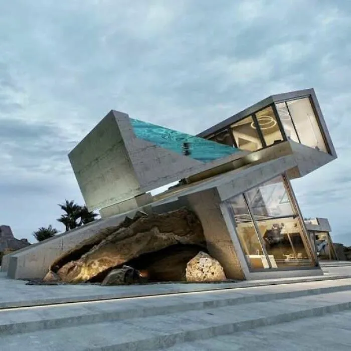Estructura futurista inclinada de concreto y vidrio con evidentes fallos de construcción.