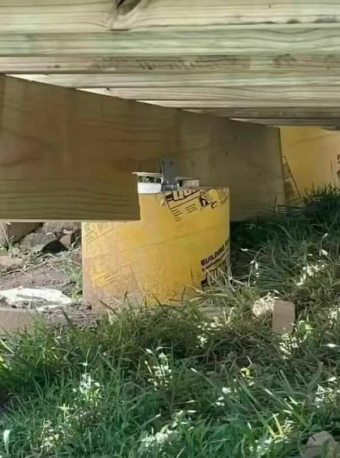 Fallos de construcción en soporte de madera de un patio sobre un cilindro de hormigón corto.