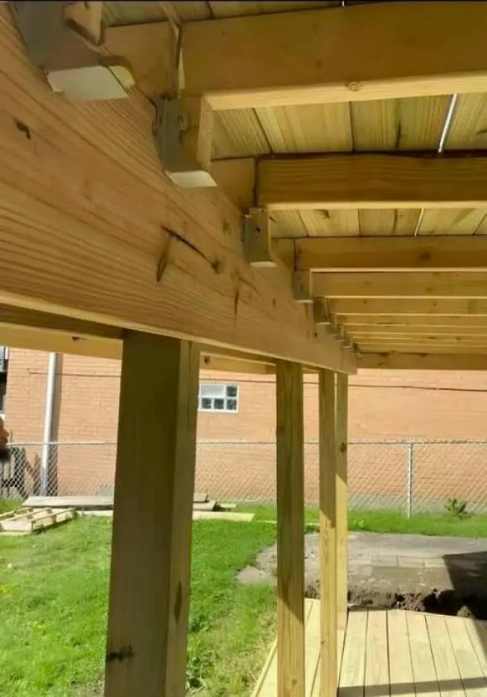 Estructura de terraza de madera con fallos de construcción en los soportes metálicos.