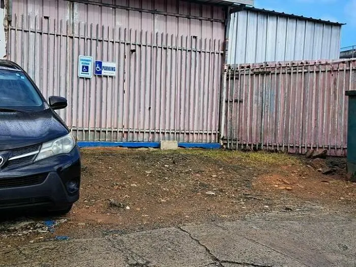 Estacionamiento reservado para discapacitados ubicado en terreno de tierra, un curioso fallo de construcción.