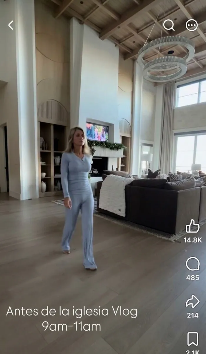 Mujer caminando en una lujosa sala de estar, mostrando a influencers haciendo el ridículo en redes sociales.