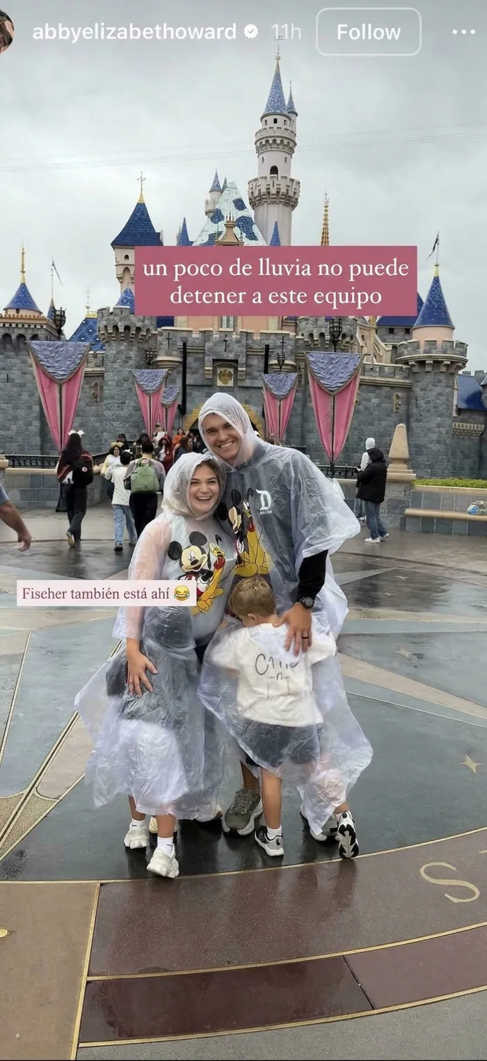 Familia de influencers en Disneyland posando con chubasqueros transparentes bajo la lluvia.