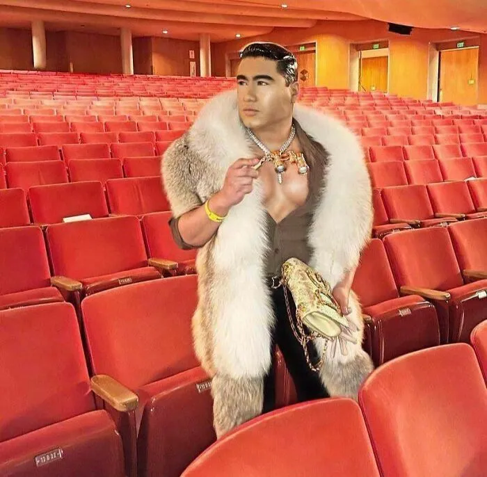 Hombre posando en un teatro con abrigo de piel, mostrando fotos tan retocadas que alteran la realidad.
