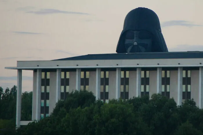 Divertidas fotos de la cabeza de Darth Vader asomándose detrás de un edificio moderno.