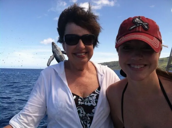 Una ballena saltando en el fondo hace que esta sea una de las divertidas fotos con genial fondo.