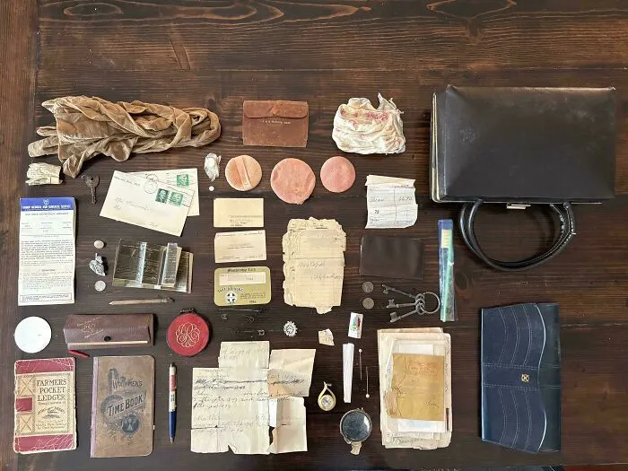 Colección de objetos efímeros antiguos sobre una mesa de madera como cartas, bolsos y documentos.