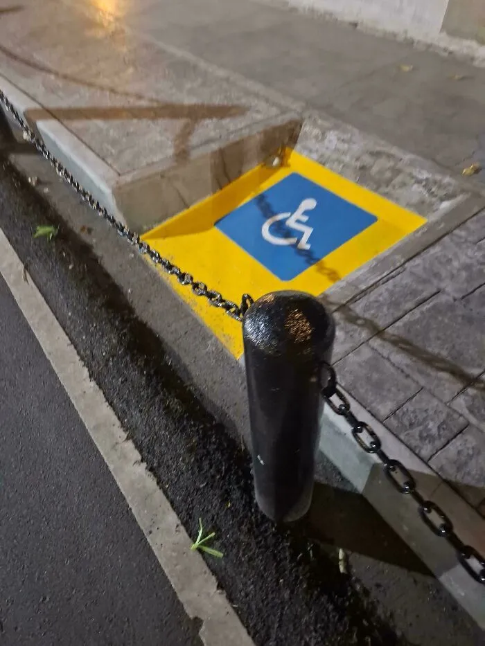 Rampa de accesibilidad para discapacitados bloqueada por una cadena, grave fallo de diseño.