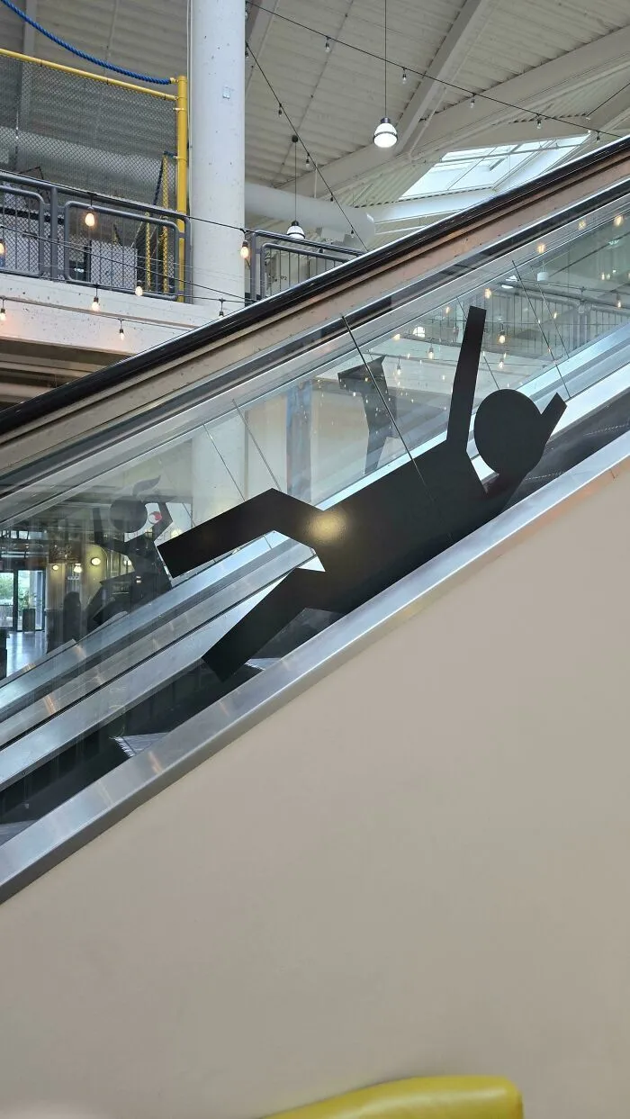 Adhesivo de silueta cayéndose en el cristal de una escalera mecánica, ejemplo de fallos de diseño.