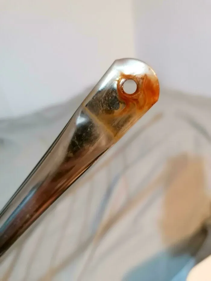 Orificio de una cuchara de metal lleno de óxido o suciedad debido a fallos de diseño en utensilios.