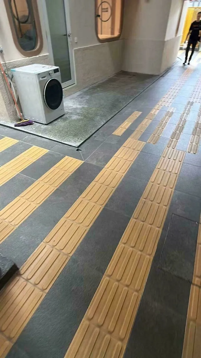 Suelo podotactil mal alineado en un pasillo exterior, un claro ejemplo de fallos de diseno.