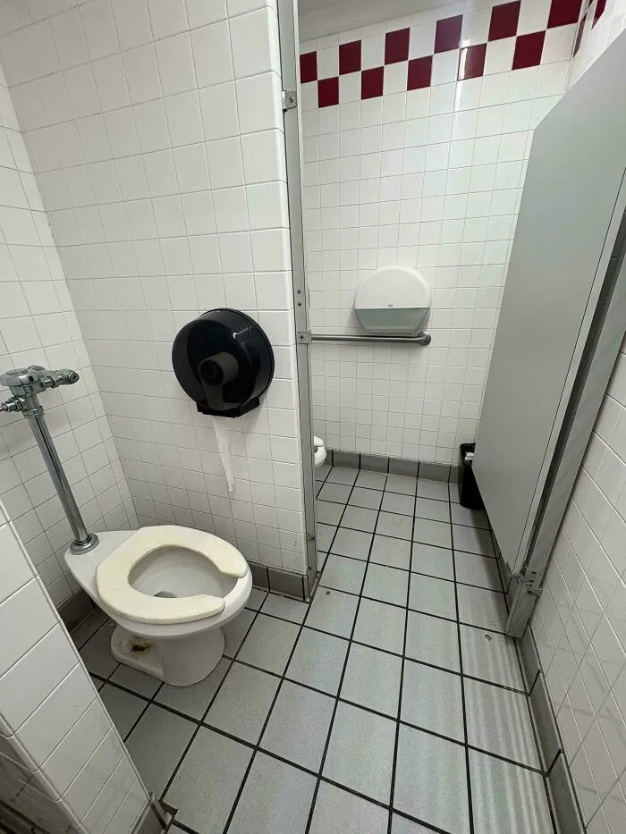 Bano publico con el dispensador de papel lejos del inodoro, evidente entre diversos fallos de diseno.