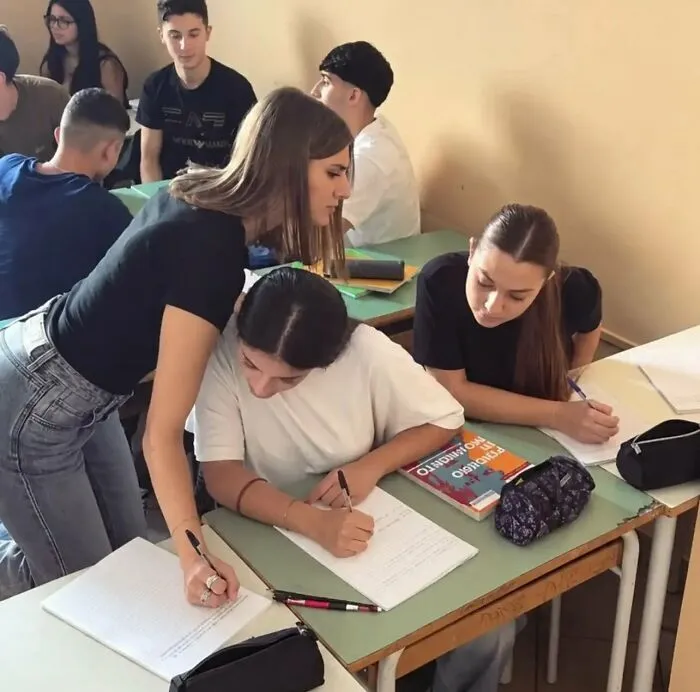Imágenes y memes sin contexto de una estudiante ayudando a otra escribiendo en su cuaderno durante la clase