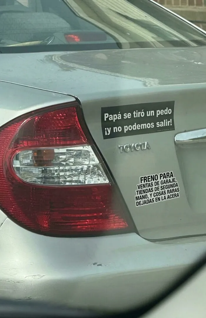 Auto gris con divertidas pegatinas en los parachoques de los coches con frases graciosas.