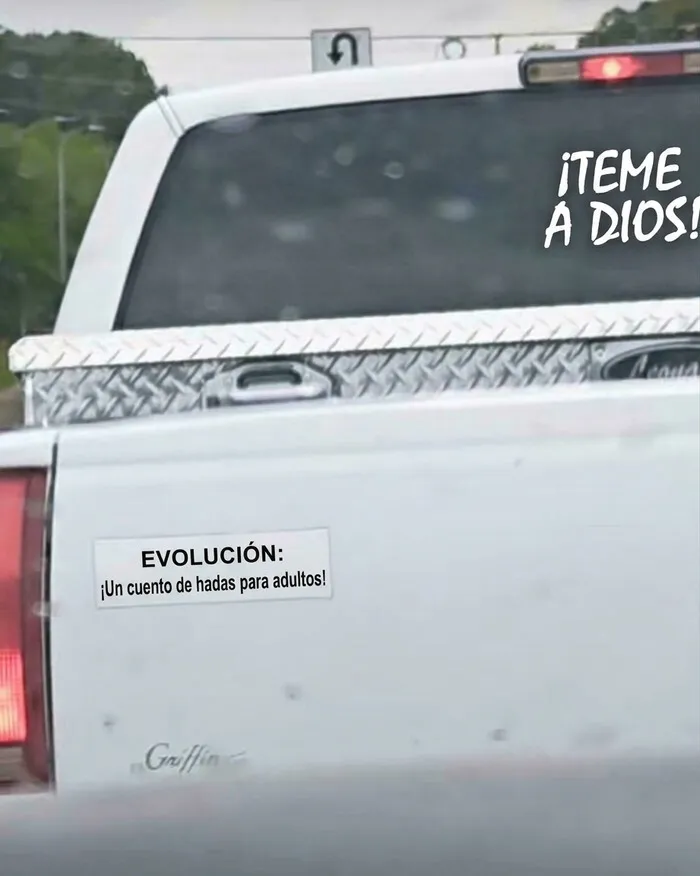 Camioneta blanca con una pegatina divertida en la parte trasera sobre la evolución.