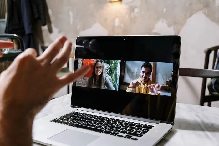 Una persona en una videollamada de trabajo en su laptop escuchando sobre trabajadores despedidos de forma remota.