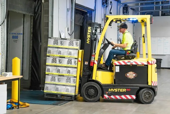 Un hombre manejando un montacargas en un almacén, representando a trabajadores despedidos en el sector logístico.