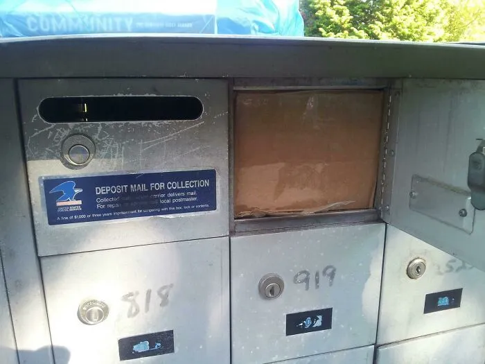 Caja atascada en un buzón de correo comunitario tras la entrega de los repartidores.