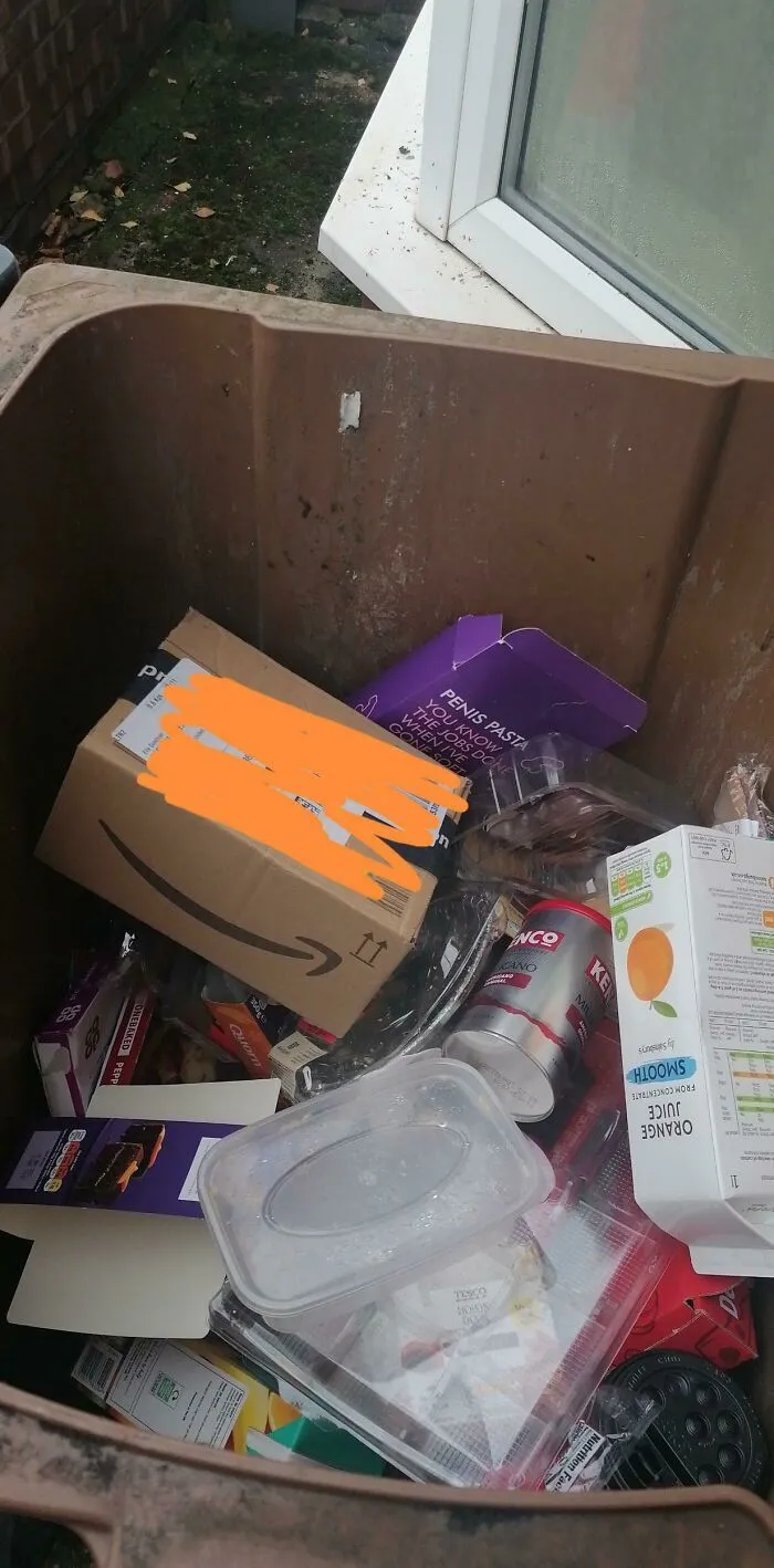 Paquete dejado por repartidores dentro de un bote de basura lleno.
