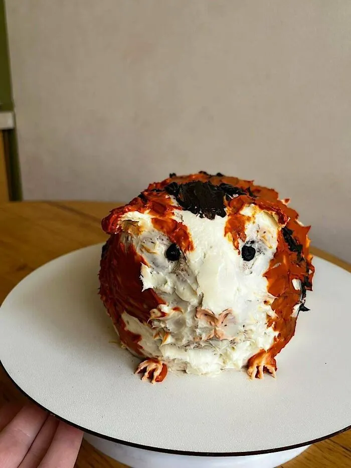 Pastel decorado con crema blanca y marrón en forma de cobaya, diseño original de repostería.