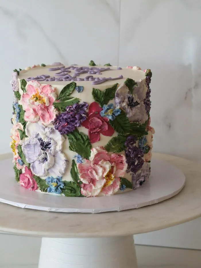 Pastel de cumpleaños decorado con flores pintadas en crema, un nivel superior en repostería.