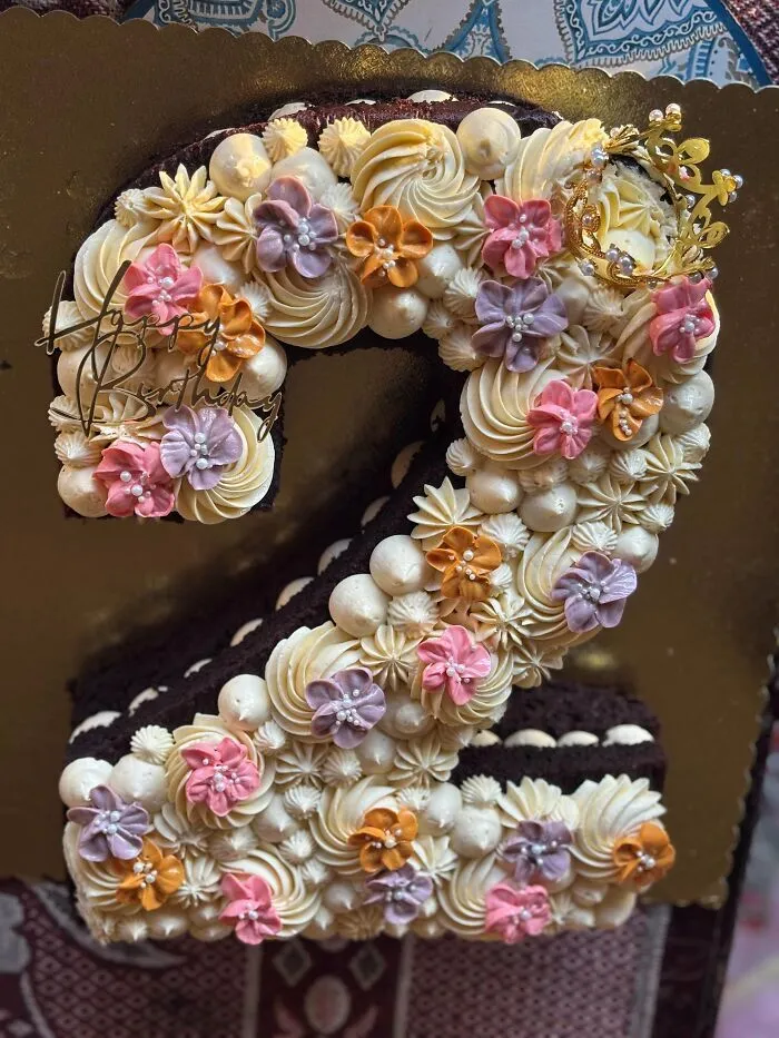 Pastel de chocolate en forma de número dos decorado con flores de crema, muestra de alta repostería.