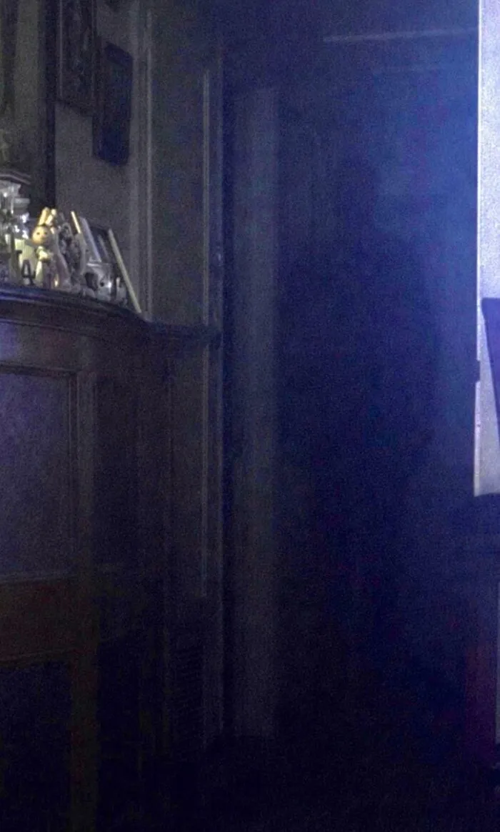 Figura oscura en el pasillo que evoca eventos aterradores en una casa nocturna.