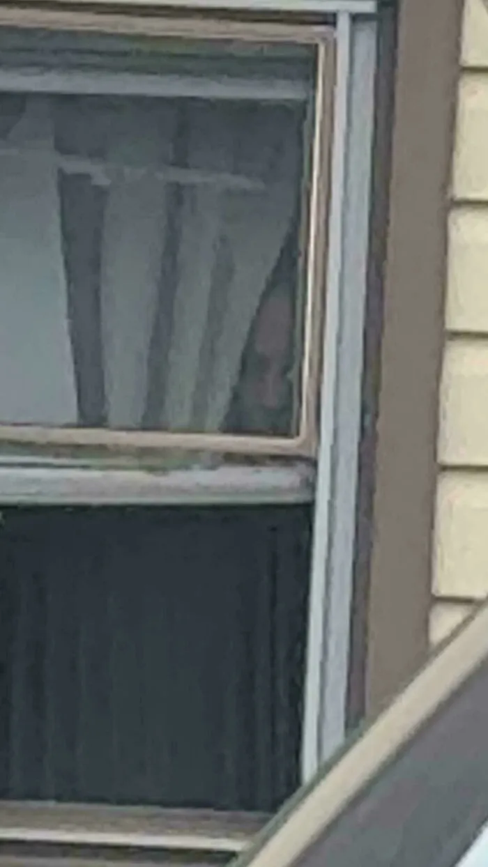 Rostro inquietante asomándose por una ventana en eventos aterradores.